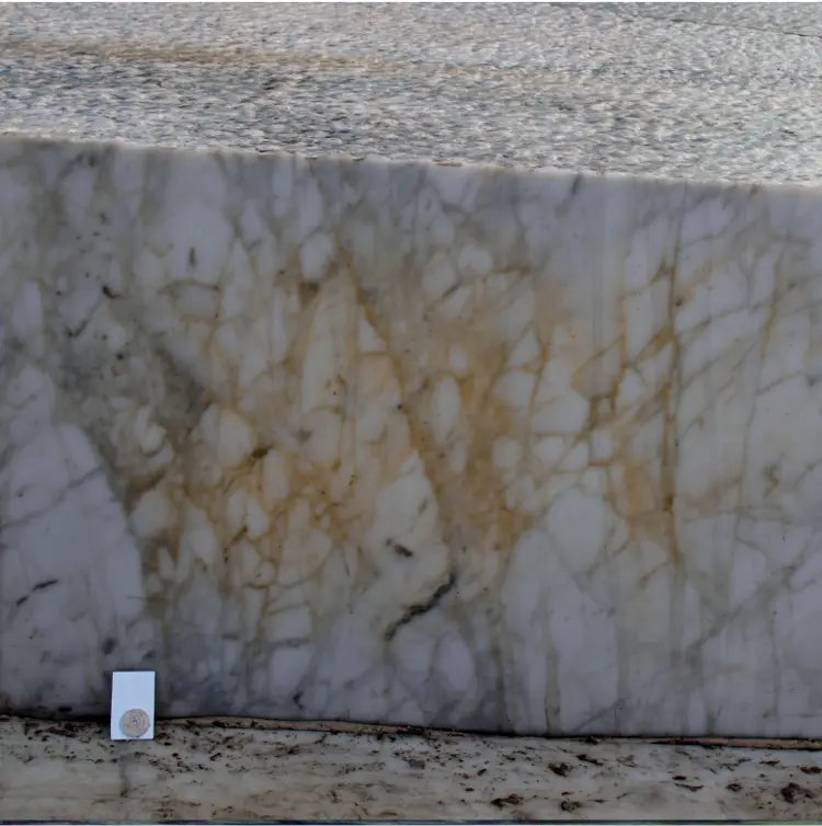 Misfarging av marmor fra Carrarra: En bit av taket til Operaen sett fra havnelageret høsten 2011. Gul misfarging er synlig på lang avstand. Pilen viser en kraftig misfarget vertikal kant.  Detaljbildet viser årsaken: Brungul farge på grunn av rustpartikler inne i selve steinen. Et velkjent forvitringsproblem med denne bergarten. Foto: Tom Andersen