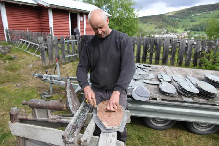 En mal sikrer at skiferlappene får samme fasong. Odd Arne Rudi risser rundt malen før han klipper til skiferen. Foto: Bygg og Bevar