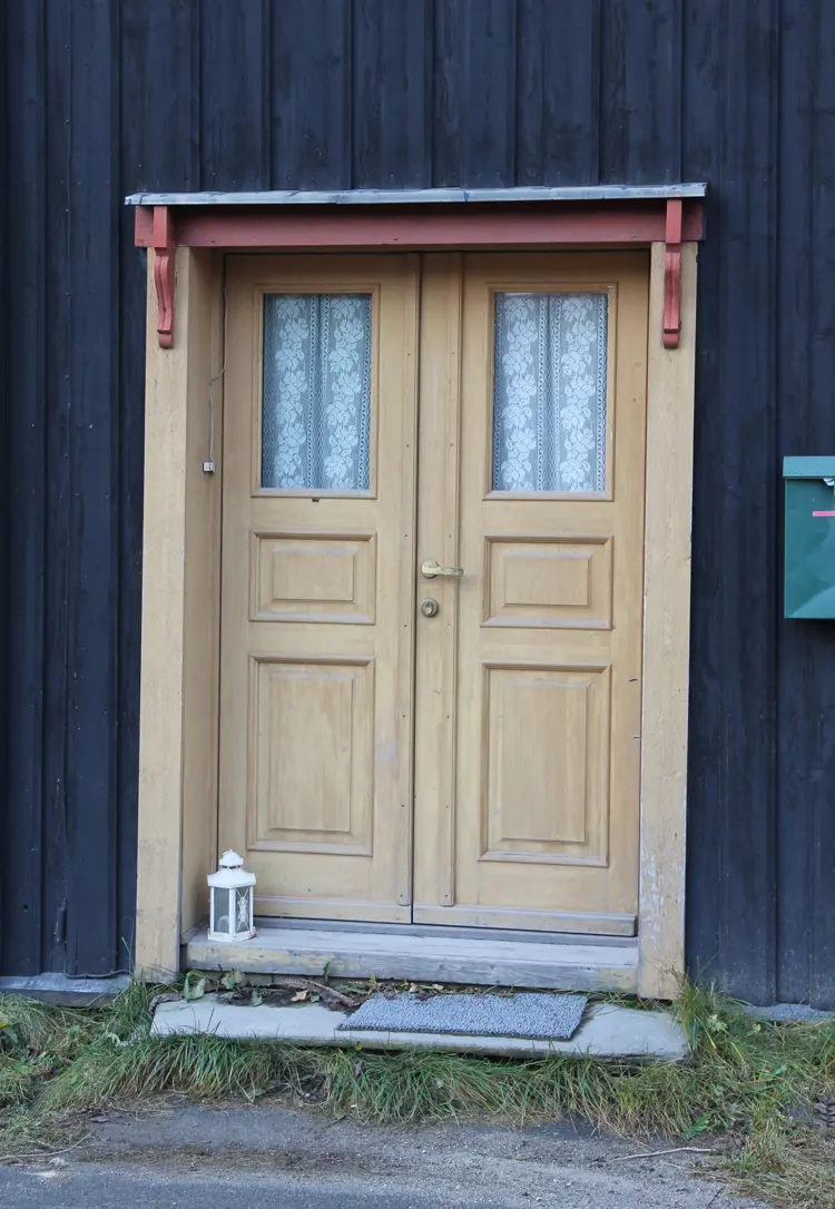 Lys okergul dør med litt rødt mot brunbeiset kledning. Røros. Foto: Christel Wigen Grøndahl, Bygg og Bevar