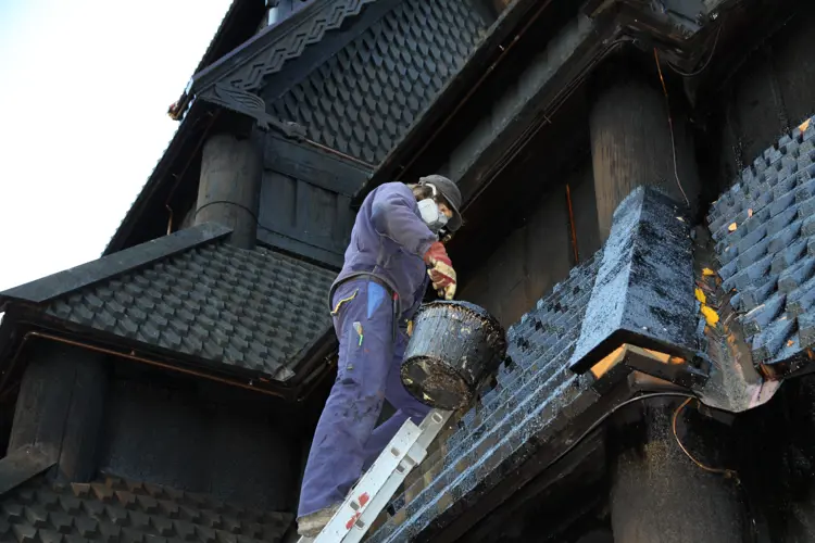 takflater i de pussigste vinkler krever mye tid på stige. Og masken er på! Tjæra utskiller skadelige gasser, spesielt ved oppvarming. Foto: Christel Wigen Grøndahl, Bygg og Bevar   