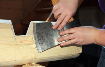 Hege Laugerud finpusser barkelaftet med øksen sin. Foto: Christer Stenby