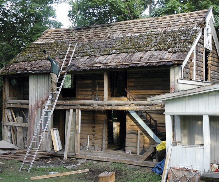 Stolt huseier i arbeid. Her er alle panler og listverk fjernet, vinduer og dører tatt ut. Noen få bord igjen på frontveggen før jobben med taket kan begynne. Foto: Norske Hjem