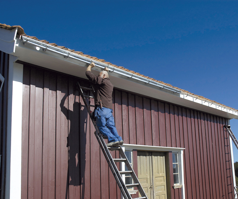 Svalgangshuset får nye sinktakrenner. Nedløpsrørene som monteres er gamle, gjenbrukte fra et rivningsklart hus i distriktet. Foto: Norske Hjem