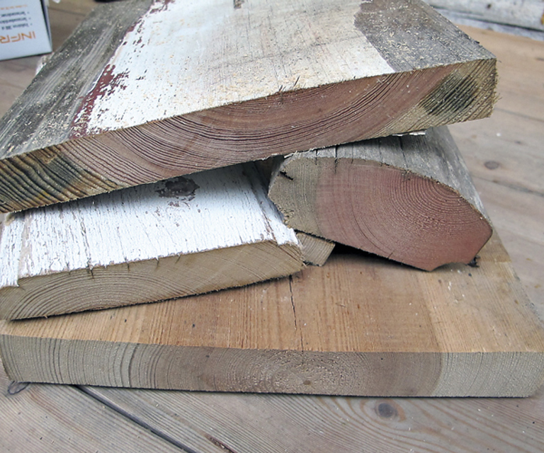 malmtømmer hvor malmen (det rødlige trevirket i sentrum) fyller en stor del av tverrsnittet på materialet. Malmen inneholder en høy ande harpiksstoffer og bidrar til at trevirket er naturlig gjennomimpregnert. I tillegg til de tette årringene, er dette optimalt i forhold til kvaliteten på tømmeret. På dette bildet vises ulike materialer fra svalgangsbygningen. Tverrsnittet viser den eksepsjonelt gode kvaliteten på materialene som ble valgt ut til dette huset. Foto: Norske Hjem