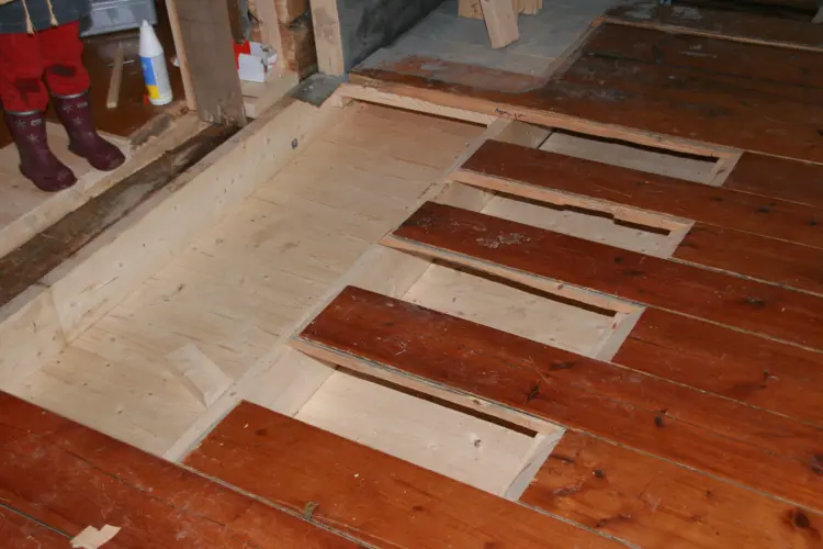 Gulv under utbedring. Bordene har vært tatt ut, dårlig bjelkelag måtte skiftes ut, og det ble etablert bedre lufting under. Hulrommet er innblåst med isofiberisolasjon. Foto: Ola H. Fjeldheim