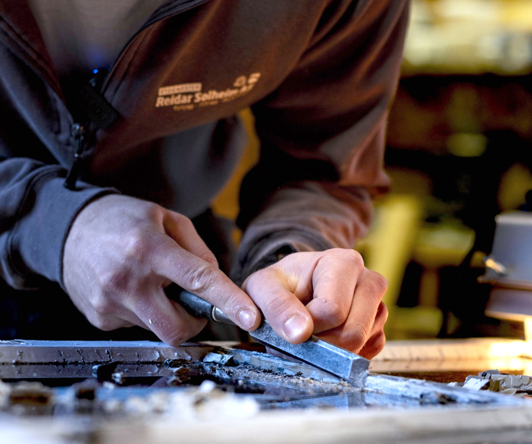 Ask fjerner kittet etter oppvarming – varme gjør det enklere å skrape uten å skade treverket. Foto: Marlen Langeland Hagen