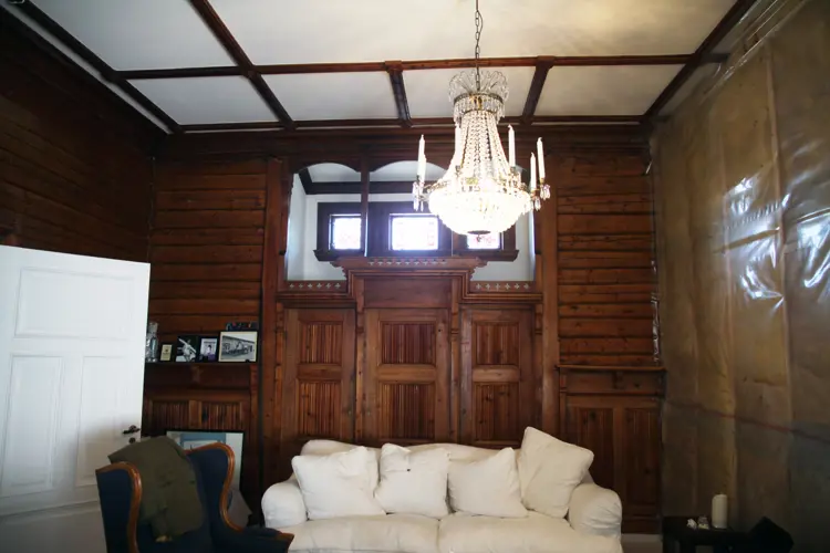 Den fineste stua er for tiden pakket inn i isolasjonsmatter der det store vinduet er tatt ut. Vinduet er for tiden til restaurering hos Gausdal snikkeri. Foto: Christel Wigen Grøndahl, Bygg og Bevar