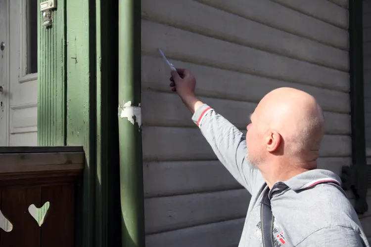 På Universitetet i Ås skal flere bygninger etterhvert settes i stand. Erixon tar en nærmere titt på en av sveitservillaene som står for tur. Her er en grundig vask og litt skraping nødvendig før det kan males. Foto: Christel Wigen Grøndahl, Bygg og Bevar