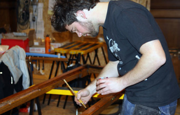Sverre Unger setter vindusrammene inn med Benarolje. Foto: CEWG