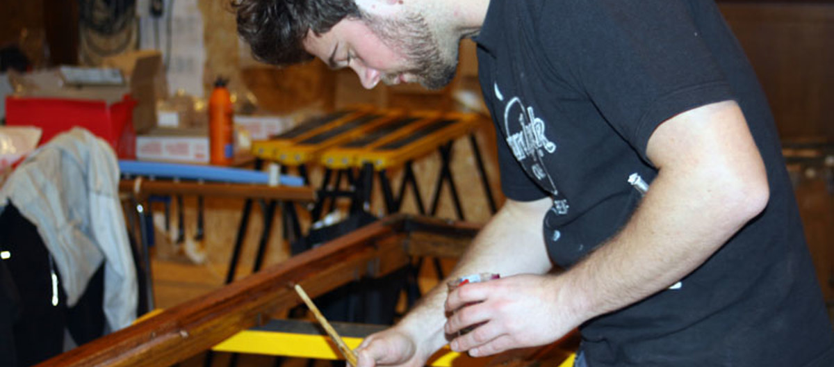 Sverre Unger setter vindusrammene inn med Benarolje. Foto: CEWG