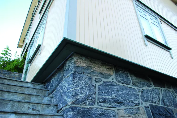 På dette bildet ses et hus hvor ytterveggen er isolert utenfra. Normalt sett ligger panelet tett på grunnmuren. Her har ettersioleringen gjort at veggen stikker svært langt ut. I dette tilfellet er vinduene flyttet tilsvarende - det er svært lite estetisk dersom vinduet blir stående innsunket inne i veggen. Foto: Per-Willy Færgestad