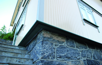 På dette bildet ses et hus hvor ytterveggen er isolert utenfra. Normalt sett ligger panelet tett på grunnmuren. Her har ettersioleringen gjort at veggen stikker svært langt ut. I dette tilfellet er vinduene flyttet tilsvarende - det er svært lite estetisk dersom vinduet blir stående innsunket inne i veggen. Foto: Per-Willy Færgestad