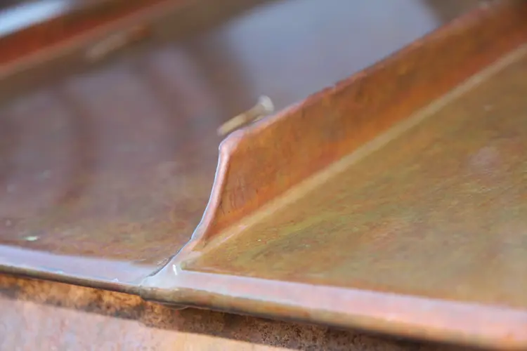 Svingt-avslutning-av-dobbeltfals-ved-takfot-paa-et-kobbertak.-Foto:-Bygg-og-Bevar