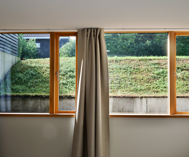 Store vindusflater i underetasjen gir godt lysinnslipp på soverommet, samtidig som man har en lun atmosfære med gardiner og utsikt mot hagen. Vinduene er laget av vinduprodusenten Meling på Kvitsøy.  