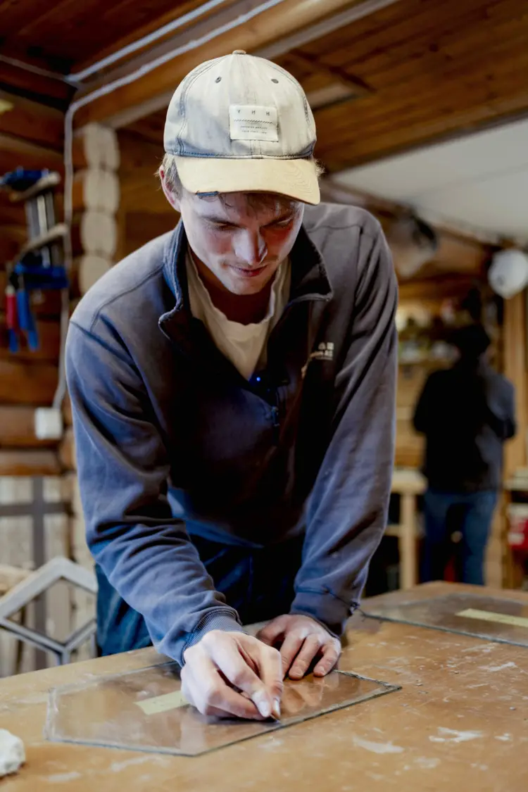Ask skraper bort gammelt kitt fra glasset. Foto: Marlen Langeland Hagen