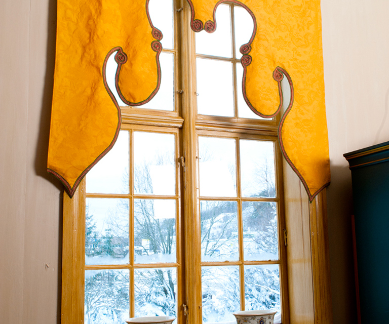 En slik glatt og foret kappe, skåret i buer og tunger, kalles lambrequin. Kappene kom på 1600-tallet og fikk en renessanse under historismen, ca 1850-1900. Lamberquinene ble gjerne kombinert med tynne, hvite sidegardiner. Foto: Kari-Marte Frøyset