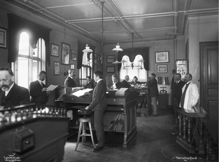 Hovedkontoret med høye pulter, stramme dresser og velfriserte barter, en eller annen gang den 25 dagen i måneden. Foto: Anders Beer Wilse