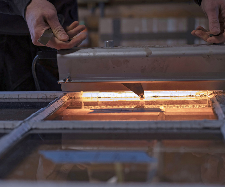 Ask demonstrerer bruk av varmelampe for å fjerne gammel kitt – unngå å rette varmen direkte på glasset, da det kan sprekke av temperaturforskjellen. Foto: Marlen Langeland Hagen